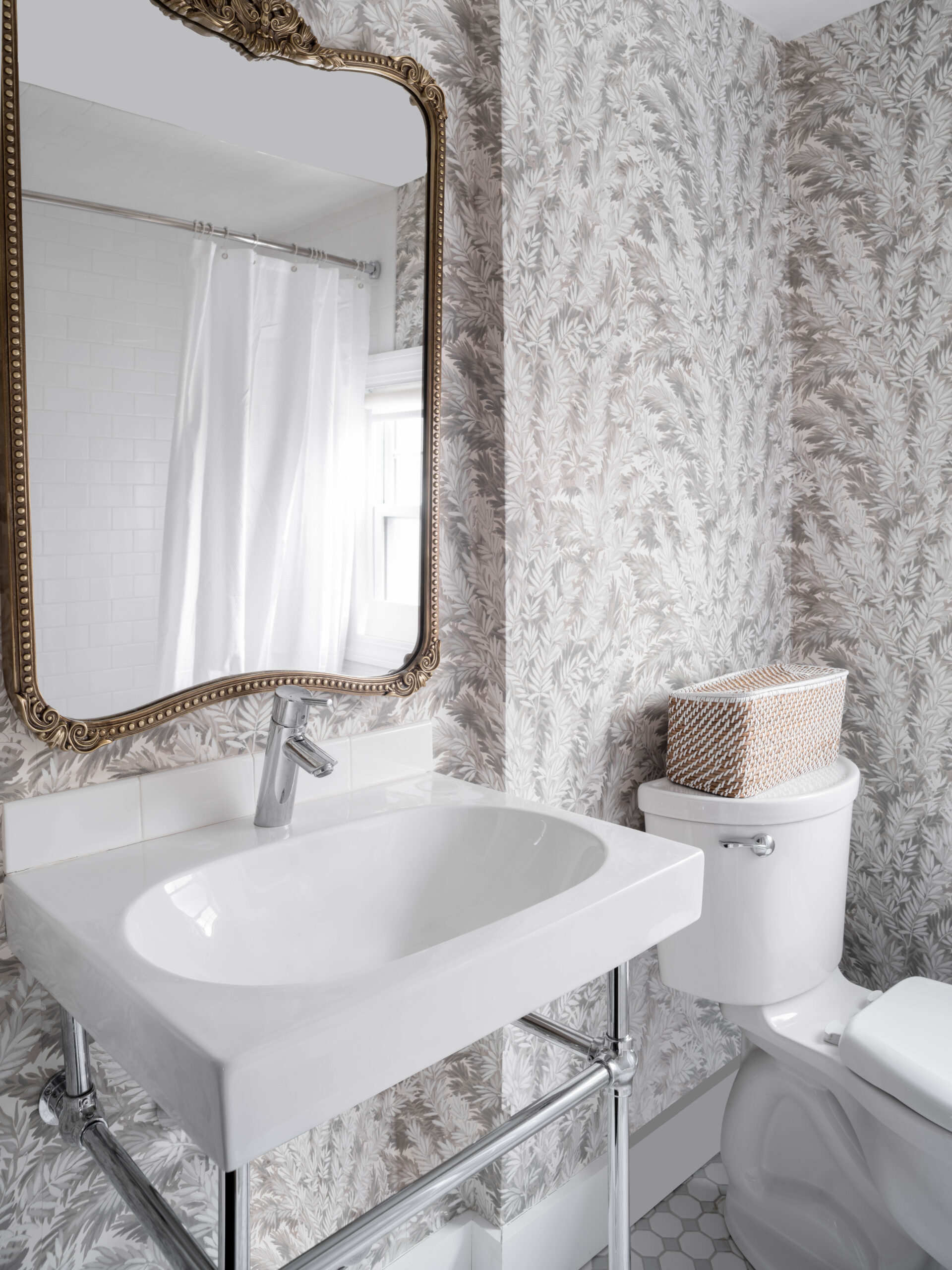 Charming powder room featuring patterned wallpaper and a classic pedestal sink, blending modern style with historic character.