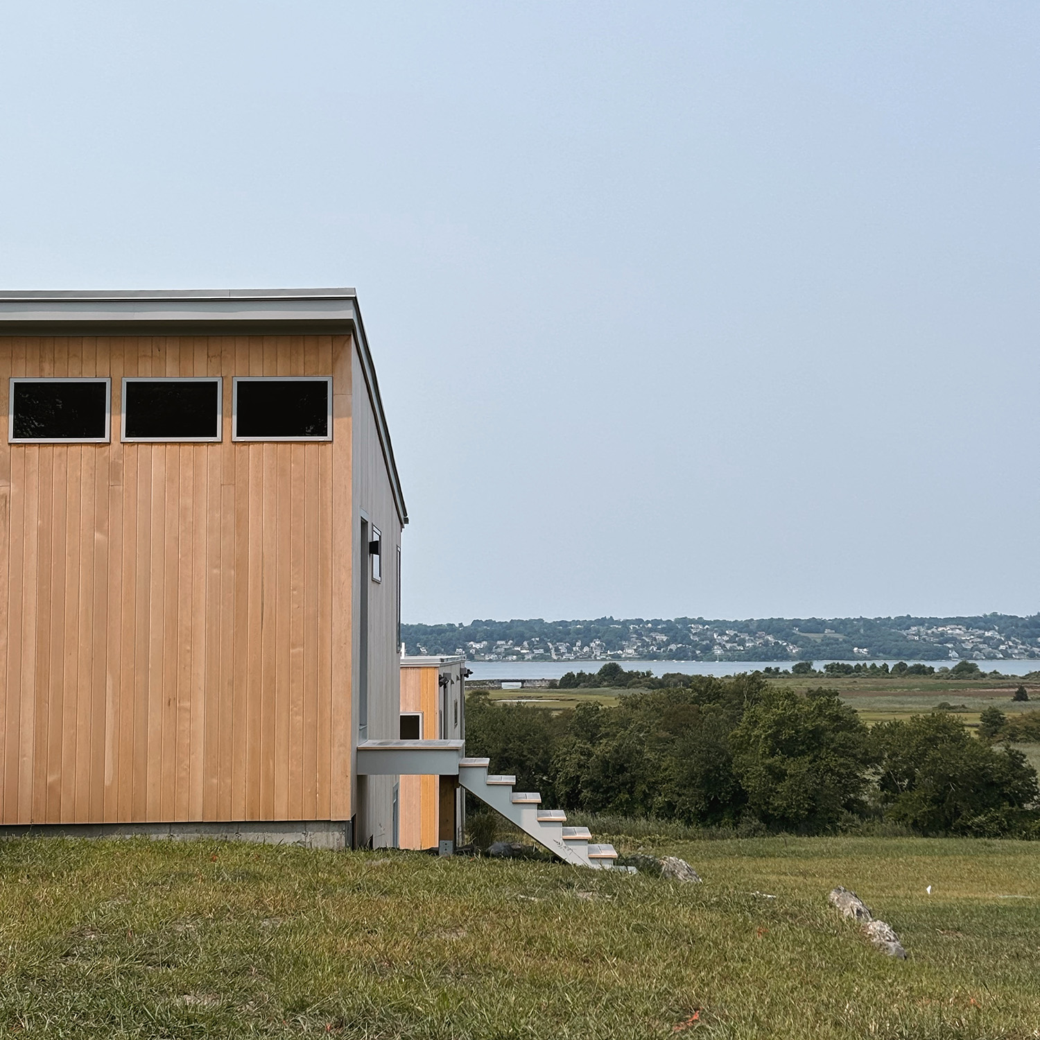 Exterior view of a modern custom coastal home overlooking the water, engineered to withstand Rhode Island weather and time.