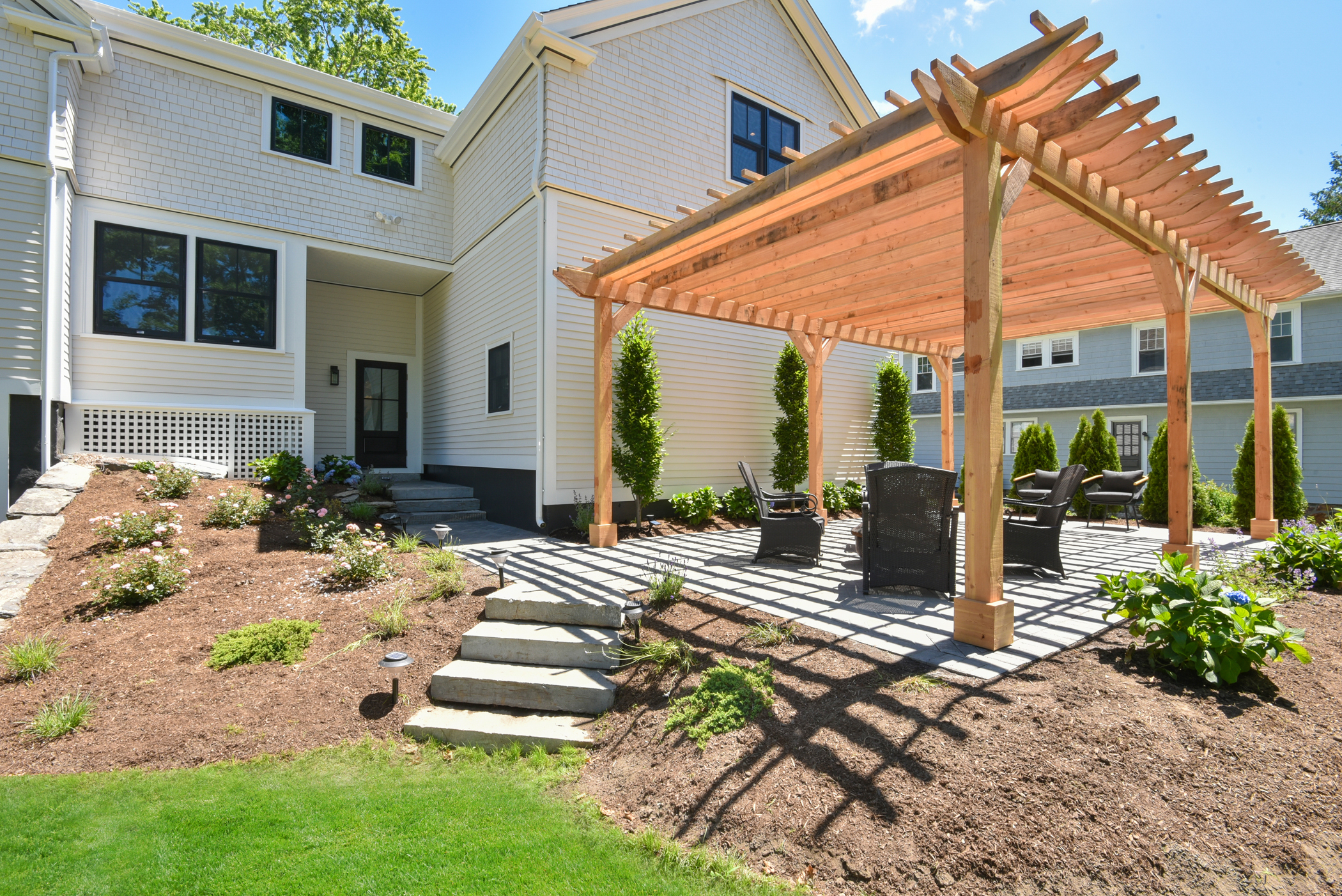 Custom wood pergola and stone patio design, creating a functional outdoor living space for entertaining.