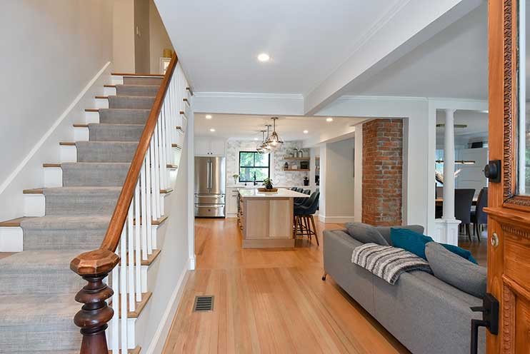 Bright entryway renovation featuring hardwood floors and a classic staircase, leading into the open-concept living area.