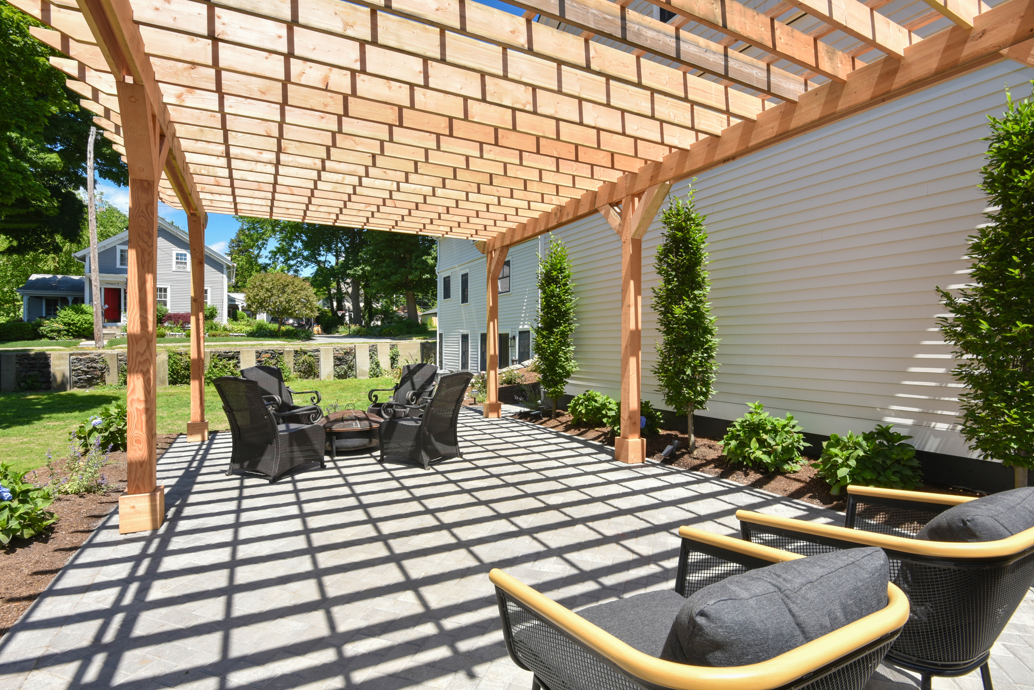 Sun-drenched outdoor terrace featuring a pergola and lounge seating, flowing into the lush gardens.